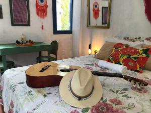 a hat on a bed with a guitar on it at Canto Alegre Pernambuco in Goiana
