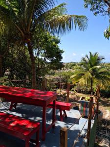 a red picnic table and benches in front of a palm tree at Canto Alegre Pernambuco in Goiana