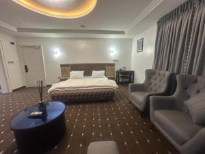 a bedroom with a bed and a couch and chairs at Peev Apartements in Abuja