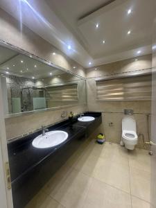 a bathroom with two sinks and a toilet and a mirror at Peev Apartements in Abuja