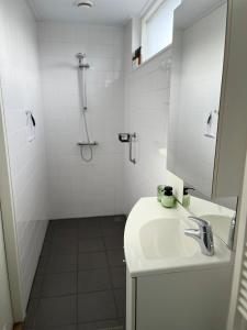 a white bathroom with a sink and a shower at B&B Bij Kaatje Thuis in Emmen