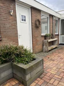 a brick house with a white garage door and plants at B&B Bij Kaatje Thuis in Emmen