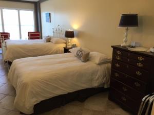 a bedroom with two beds and a dresser with a lamp at The Inn on the Wharf in Lubec