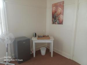 a small white table in a room with a painting at Oranje Air B&B in Alexander Bay