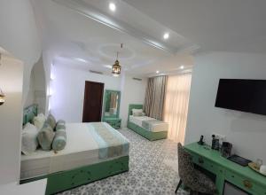a bedroom with a bed and a flat screen tv at Dar Lala Fatma in Le Lido