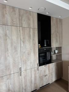 a kitchen with wooden cabinets and a microwave at Locusdo apartment Nr 27 in Vilnius