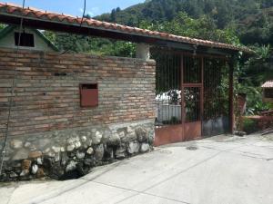 a brick building with a red door and a stone wall at Acogedora cabaña Hospedaje Mérida in Mérida