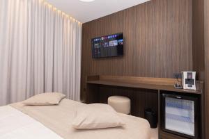 a bedroom with a bed and a tv on the wall at Quartz Hotel Vlore in Vlorë
