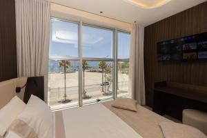 a bedroom with a bed and a large window at Quartz Hotel Vlore in Vlorë