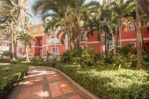 a red building with palm trees in front of it at Decameron San Luis - All Inclusive in San Andrés