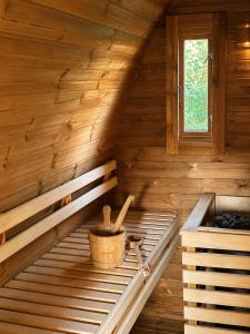a wooden sauna with a bucket and a window at KOPA LIVING seaside holiday homes in Nida