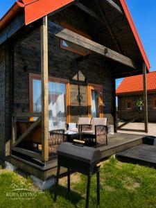 a log cabin with a deck with chairs and a table at KOPA LIVING seaside holiday homes in Nida
