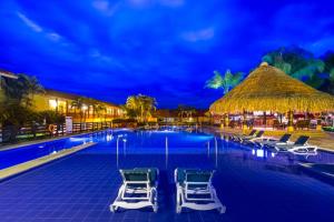 a resort pool with chairs and a thatched roof at Decameron Panaca - All Inclusive in Quimbaya