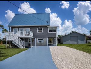 a house with a blue roof and a gravel driveway at Driftwood Getaway Vacation home in Fort Myers Beach