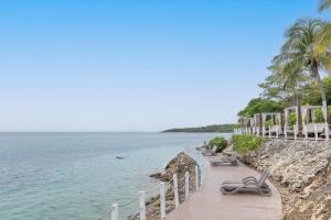 a wooden walkway next to the ocean with benches at Decameron Barú - All Inclusive in Playa Blanca