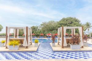 a pool at a resort with umbrellas and potted plants at Decameron Barú - All Inclusive in Playa Blanca