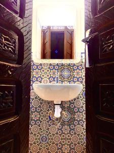 a white sink in a bathroom with a mirror at Riad Nezha avec piscines jacuzzi parking à quelques minutes à pied du centre-ville in Marrakesh