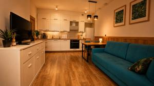 a living room with a blue couch and a kitchen at Szmaragdowa Przystań - apartament z parkingiem blisko Parku Zdrojowego i Tężni in Busko-Zdrój