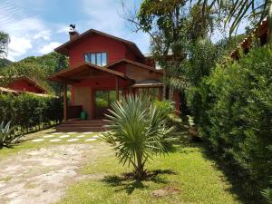 a red house with a palm tree in front of it at Verde Mauá Chales in Visconde De Maua