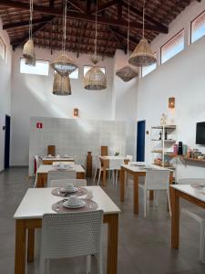 a dining room with tables and chairs and pendant lights at Boulevard Pousada Boutique in Guaramiranga