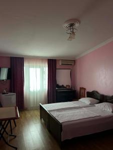 a bedroom with two beds and a desk and a window at Hotel Lika in Batumi