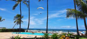a swimming pool with palm trees and a kite in the sky at KORA MAR - Taipu de Fora - BA in Barra Grande