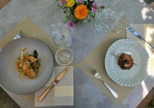 a table with two plates of food and wine glasses at Fischerhof in Cortaccia