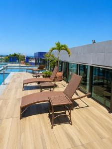a deck with chairs and a pool on a building at Apartamento com Piscina Rooftop e Hidro perto do Centro e da Praia, Porto Blue Porto de Galinhas in Porto De Galinhas