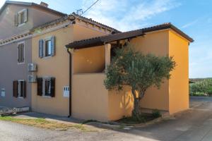 a yellow house with a tree in front of it at Terra rossa rooms in Čepljani