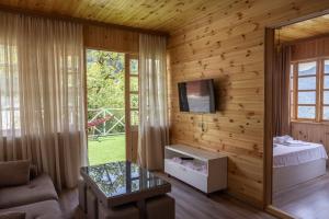 a living room with wooden walls and a tv and a couch at Laguna Villa Cottages in Chinkadzeebi