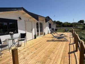 a wooden deck with chairs and a table on a house at Möllergårdens Stugor in Ängelholm +18 photos