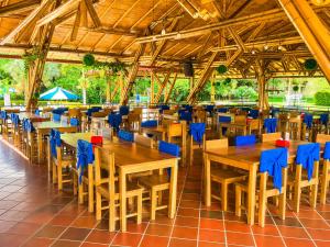 a restaurant with wooden tables and blue chairs at Hotel Takuara in Vergara