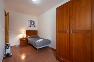 a bedroom with a bed and a wooden cabinet at Apartamento By Llu in Alcalá la Real