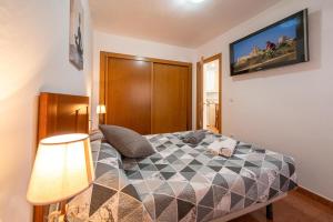a bedroom with a bed and a tv on the wall at Apartamento By Llu in Alcalá la Real