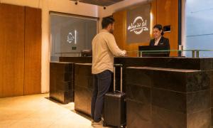 a man with a suitcase standing at a counter with a woman at Alto del Sol Costanera Antofagasta in Antofagasta