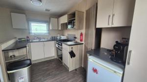a small kitchen with white cabinets and a stove at K & K Caravan Southview in Skegness