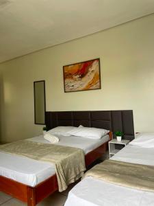 a bedroom with two beds and a painting on the wall at Alameda Hotel Centro in Garanhuns +10 photos