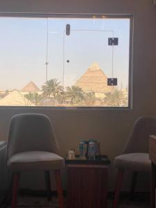 a room with two chairs and a window with a pyramid at Irit pyramids inn in Cairo
