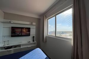 a bedroom with a large window and a television at Studio Nova Betânia - Barreto - in Mossoró