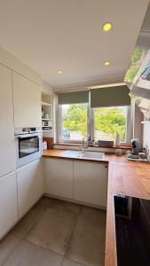 a kitchen with white cabinets and a large window at Haus SandRast in Westerland