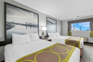 ein Hotelzimmer mit zwei Betten und einem großen Fenster in der Unterkunft Super 8 by Wyndham Saskatoon Near Saskatoon Airport in Saskatoon + 47 Fotos