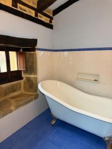 a bath tub in a bathroom with blue tiles at Museo de las Campanas, Vierna in San Bartolomé de Meruelo +50 photos