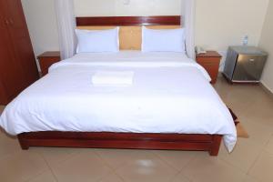 a bedroom with a large bed with white sheets at Bavah Airport Hotel in Entebbe +9 photos