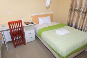 a bedroom with a bed and a desk and a chair at Bavah Airport Hotel in Entebbe