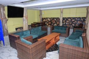 a living room with a couch and chairs and a television at Bavah Airport Hotel in Entebbe