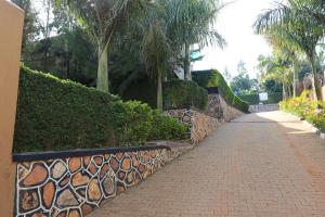 a brick path with a fence and palm trees at Bavah Airport Hotel in Entebbe