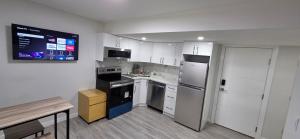 a kitchen with white cabinets and black appliances at La Rose des Prairies -The Prairie Rose in Calgary