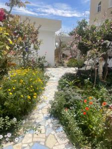 a garden with flowers and a stone walkway at Maison Souad Guest House in Chott Meriem