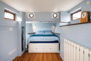 a small bedroom with a bed and two windows at Historic Dutch Barge, Idyllic location in London