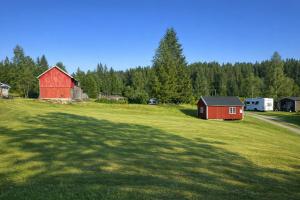 a large field with a red barn and a house at Turifoss Camping Tent pitch in Svedjan